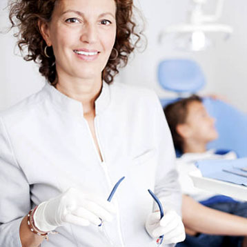 Smiling female dentist with young patient in the background